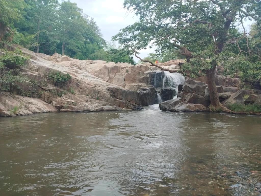 Bhainsaodar Waterfall cascading over natural stone ledges into a clear forest pool in Kabirdham