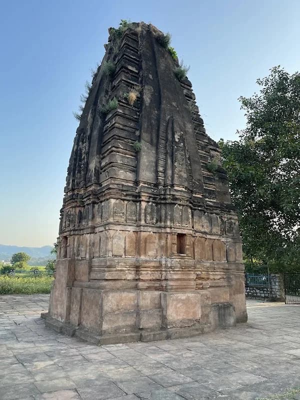 Serene stone and brick shikhara of 14th-century Cherki Mahal surrounded by green trees in Kawardha
