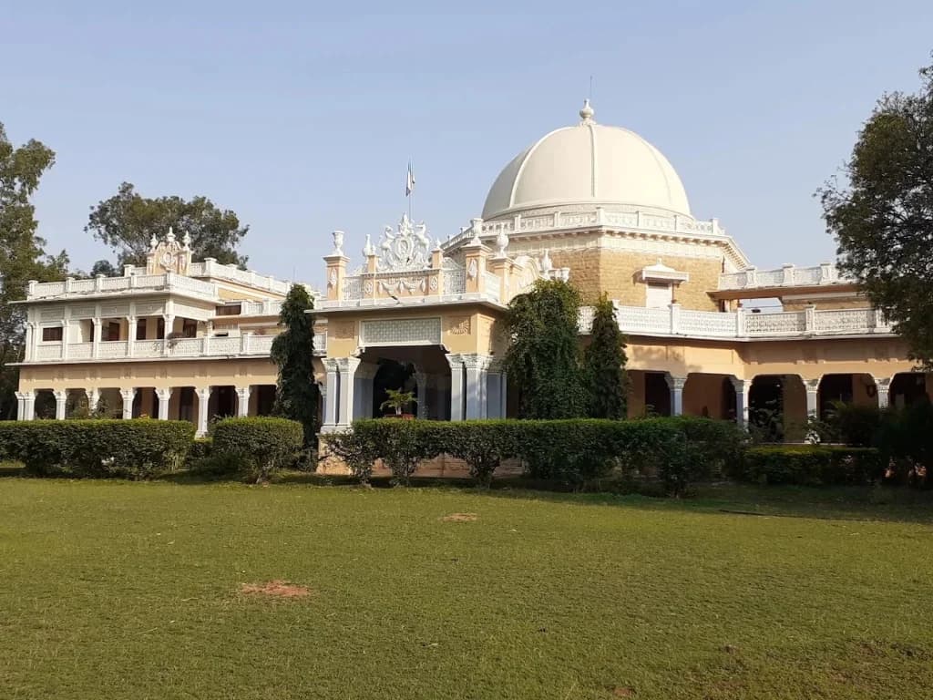 Grand stone facade and iconic central dome of Kawardha Palace overlooking the green palace grounds