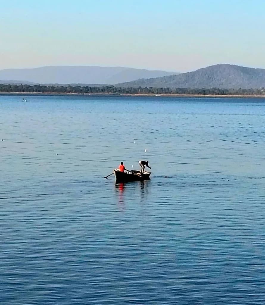 Paddle boats moored near jetty at Sarodha Reservoir with sunset over mountain hills